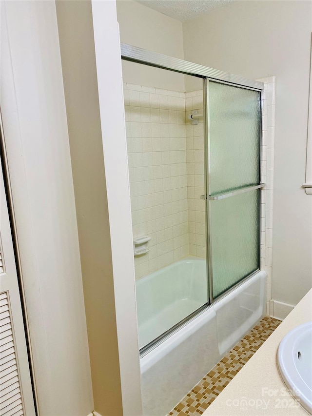 bathroom featuring combined bath / shower with glass door and a sink