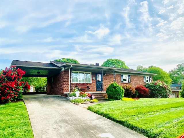 ranch-style home with brick siding, driveway, a front yard, and a carport