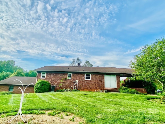 rear view of house featuring brick siding and a lawn