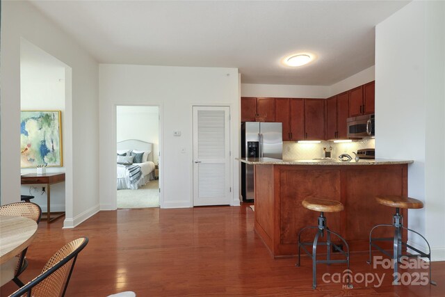 721 Governor Morrison St Unit 520, Charlotte, NC 28211 - kitchen with stainless steel appliances, wood finished floors, light stone counters, a peninsula, and backsplash