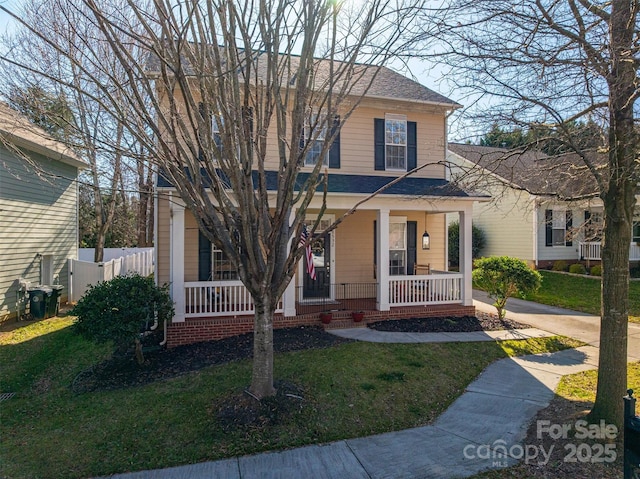 traditional-style house featuring roof with shingles, a porch, and a front yard