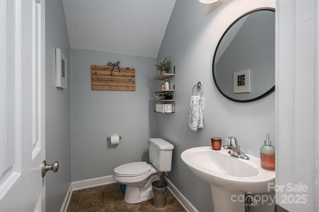 bathroom with baseboards, a sink, lofted ceiling, and toilet