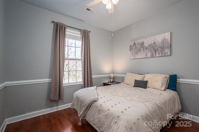 bedroom featuring visible vents, baseboards, wood finished floors, and multiple windows