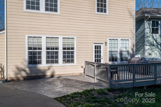 rear view of property featuring a wooden deck and a patio area