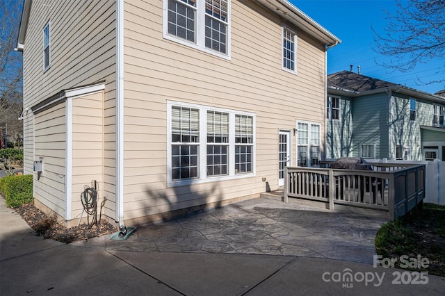 rear view of property featuring a wooden deck and a patio area