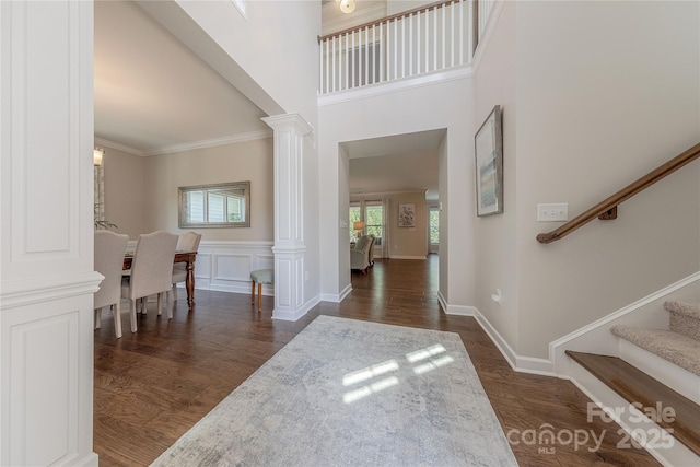 foyer with ornate columns, ornamental molding, dark wood-style floors, and stairway
