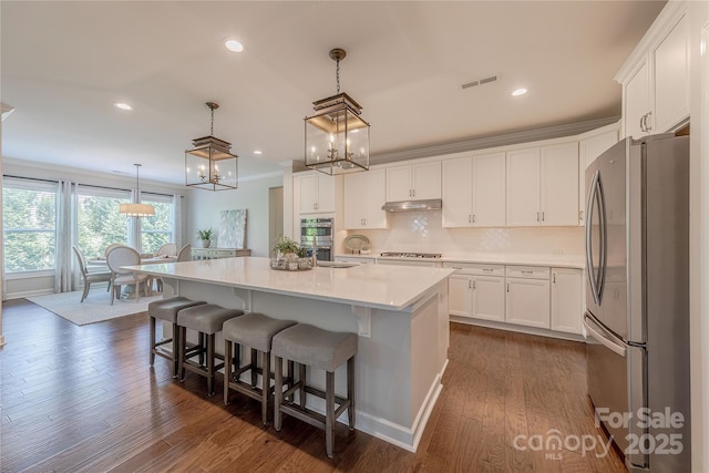 kitchen with visible vents, white cabinetry, under cabinet range hood, a notable chandelier, and stainless steel appliances