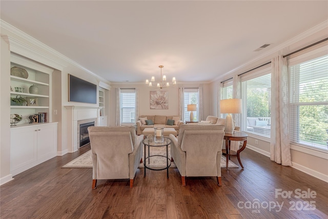 living room with a chandelier, ornamental molding, and a healthy amount of sunlight