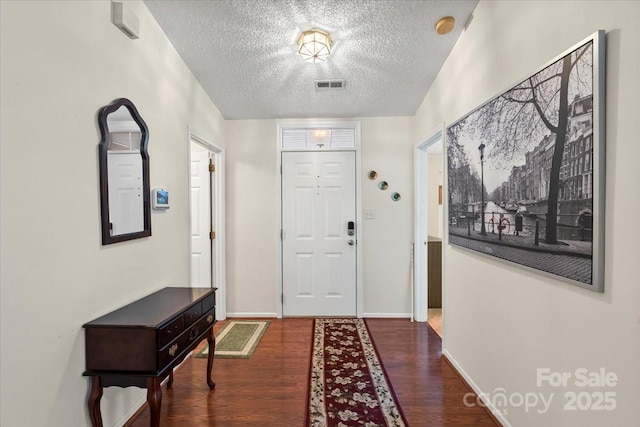 entryway with baseboards, a textured ceiling, visible vents, and wood finished floors