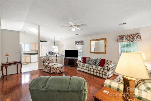 living area with ceiling fan, a textured ceiling, visible vents, vaulted ceiling, and wood finished floors