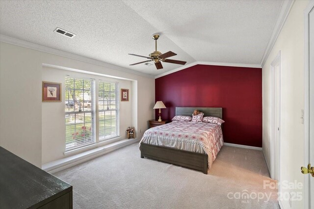 carpeted bedroom with crown molding, ceiling fan, visible vents, baseboards, and vaulted ceiling