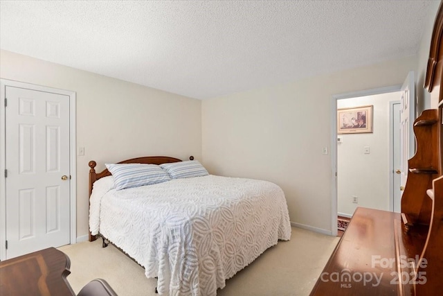bedroom with a textured ceiling, light colored carpet, and baseboards