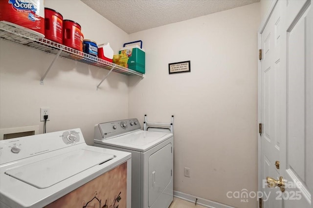 clothes washing area featuring a textured ceiling, laundry area, and washing machine and dryer