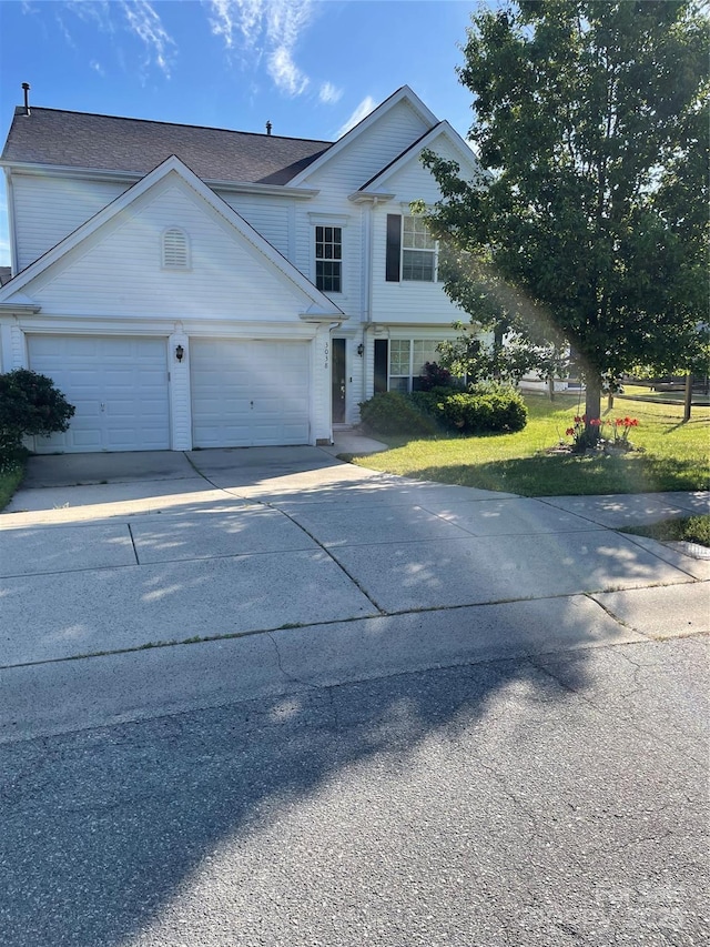 traditional-style home featuring an attached garage, driveway, and a front yard