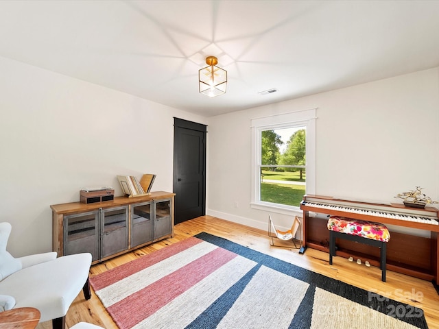 living area featuring baseboards, visible vents, and wood finished floors