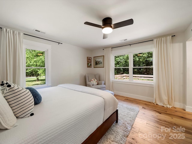 bedroom with baseboards, light wood finished floors, and visible vents