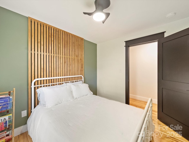 bedroom featuring light wood-type flooring, a ceiling fan, and baseboards