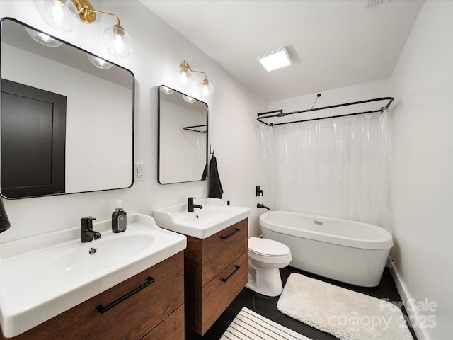 full bath with toilet, tile patterned floors, two vanities, and a sink