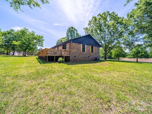 back of property featuring a deck, cooling unit, brick siding, crawl space, and a yard