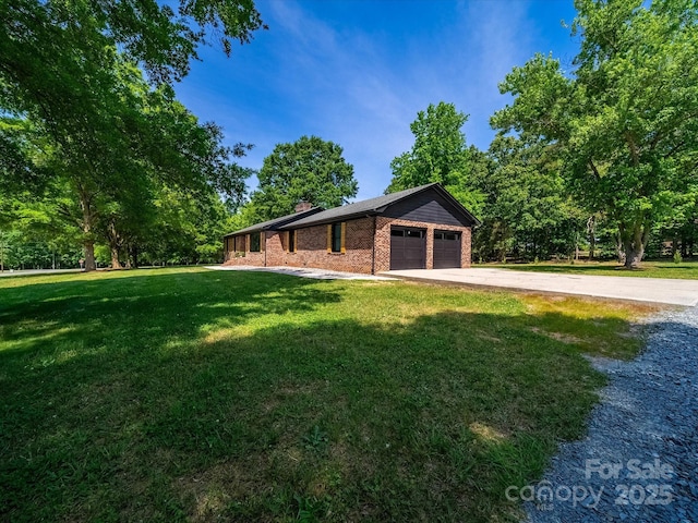 view of front of property featuring an attached garage, brick siding, a front yard, a chimney, and driveway