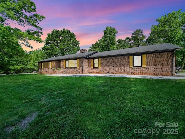 view of front of property featuring brick siding, a yard, and a chimney