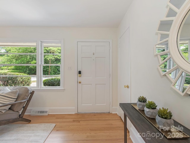 foyer entrance with visible vents, light wood-style flooring, baseboards, and a healthy amount of sunlight