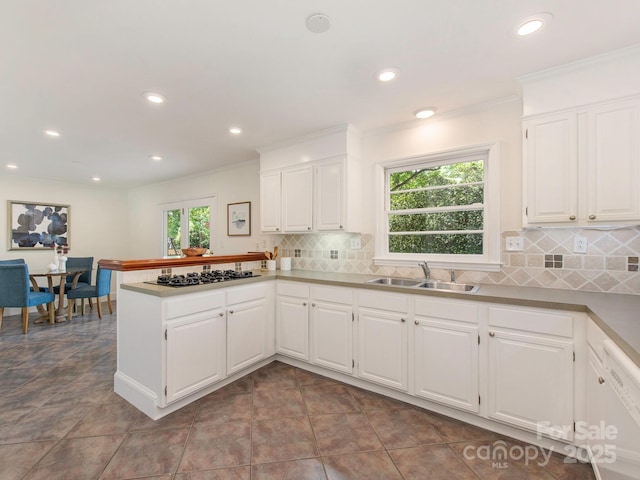 kitchen featuring a peninsula, recessed lighting, a healthy amount of sunlight, and a sink