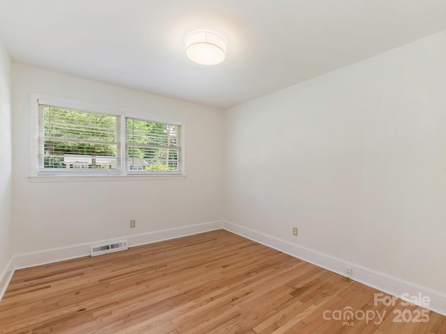 empty room featuring baseboards, visible vents, and light wood-style floors