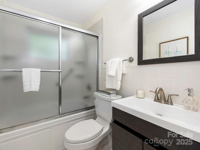 full bathroom with decorative backsplash, tile walls, vanity, toilet, and enclosed tub / shower combo