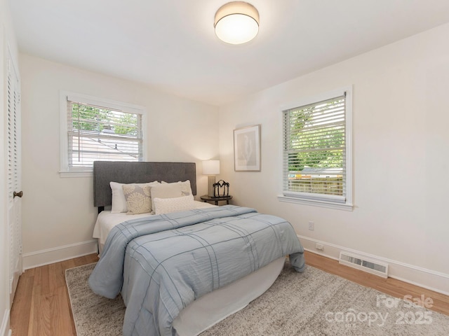 bedroom with baseboards, wood finished floors, and visible vents