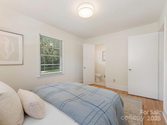 bedroom featuring light wood-style floors, connected bathroom, and baseboards