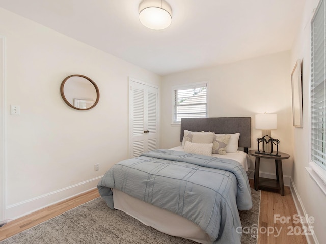 bedroom featuring baseboards, wood finished floors, and a closet