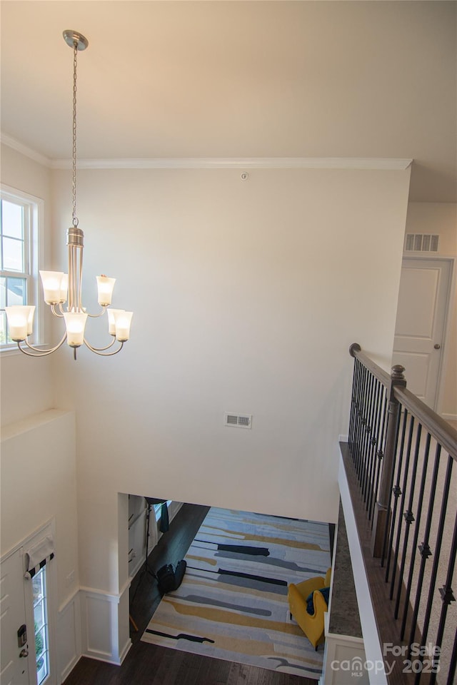 staircase featuring visible vents, ornamental molding, and an inviting chandelier