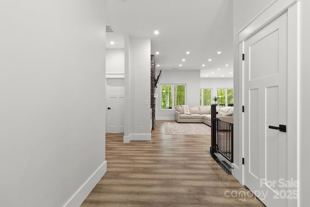corridor with baseboards, recessed lighting, wood finished floors, and visible vents