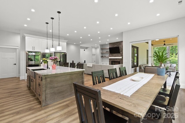 dining area featuring recessed lighting, light wood-style flooring, visible vents, and a fireplace