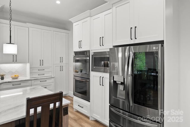 kitchen with light stone counters, light wood-style floors, appliances with stainless steel finishes, and white cabinets