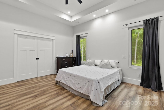bedroom with baseboards, multiple windows, recessed lighting, and wood finished floors