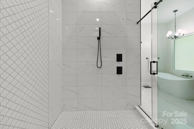 bathroom with an inviting chandelier, a freestanding bath, and a shower stall