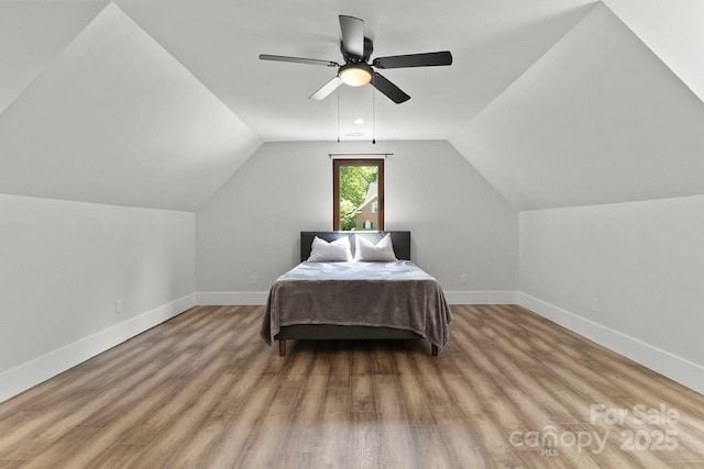 bedroom with baseboards, ceiling fan, wood finished floors, and lofted ceiling