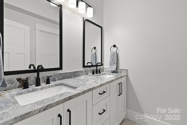 bathroom featuring double vanity, baseboards, and a sink