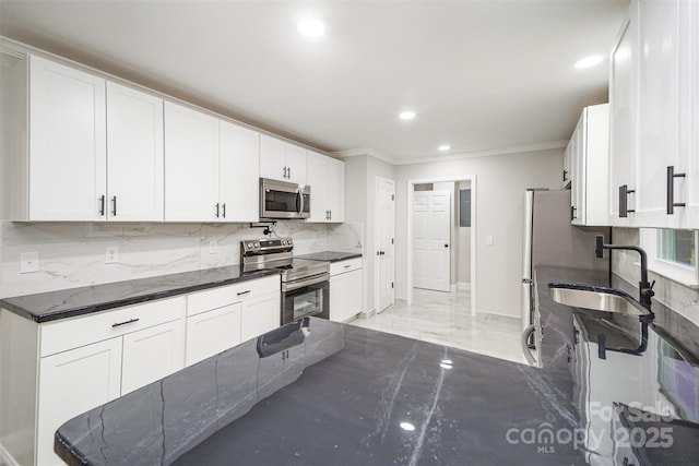 kitchen with a sink, dark stone countertops, stainless steel appliances, decorative backsplash, and ornamental molding