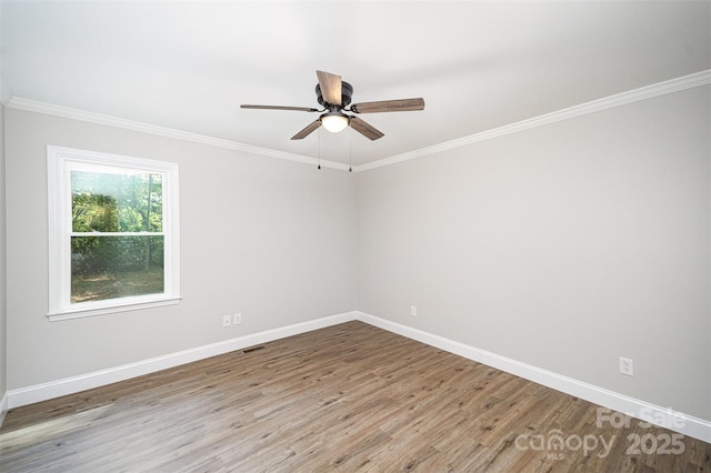 unfurnished room with crown molding, ceiling fan, baseboards, wood finished floors, and visible vents