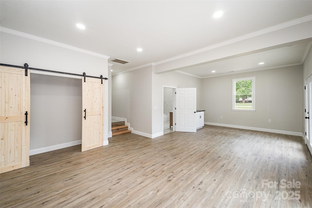 below grade area featuring light wood-style floors, recessed lighting, a barn door, and visible vents