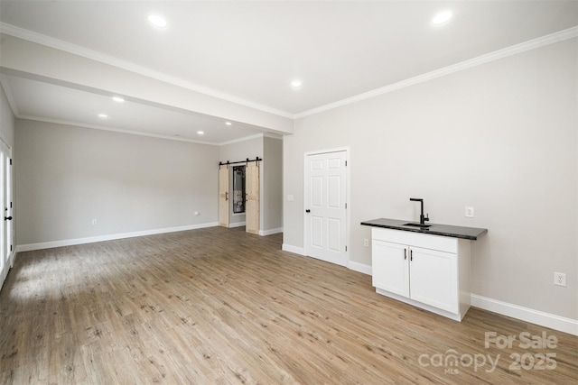 spare room with recessed lighting, crown molding, light wood finished floors, and a barn door