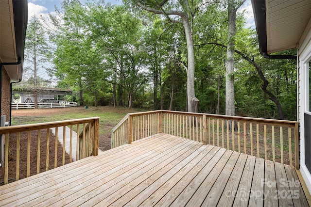 wooden terrace featuring a lawn and fence