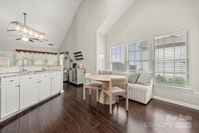 dining room featuring high vaulted ceiling, dark wood-style flooring, ceiling fan, and baseboards