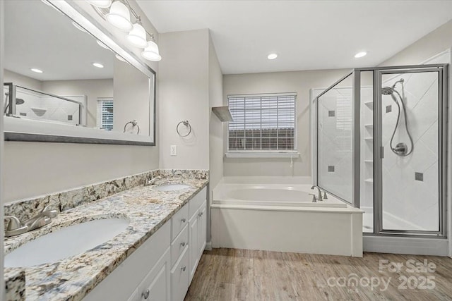 full bath featuring wood finished floors, a shower stall, a garden tub, double vanity, and recessed lighting