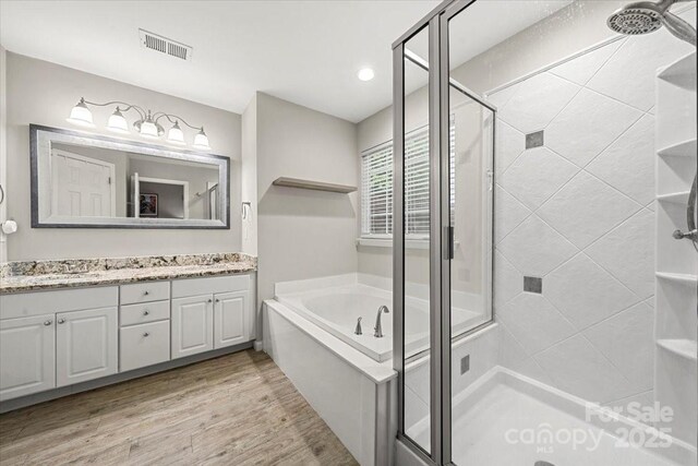 bathroom featuring a stall shower, a bath, vanity, wood finished floors, and recessed lighting
