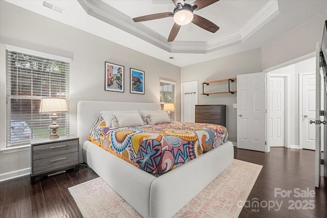 bedroom featuring ornamental molding, a raised ceiling, dark wood-style floors, baseboards, and ceiling fan