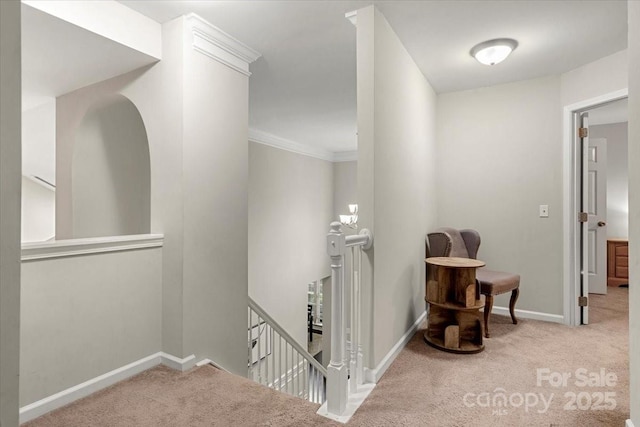 corridor with an upstairs landing, carpet flooring, baseboards, and crown molding